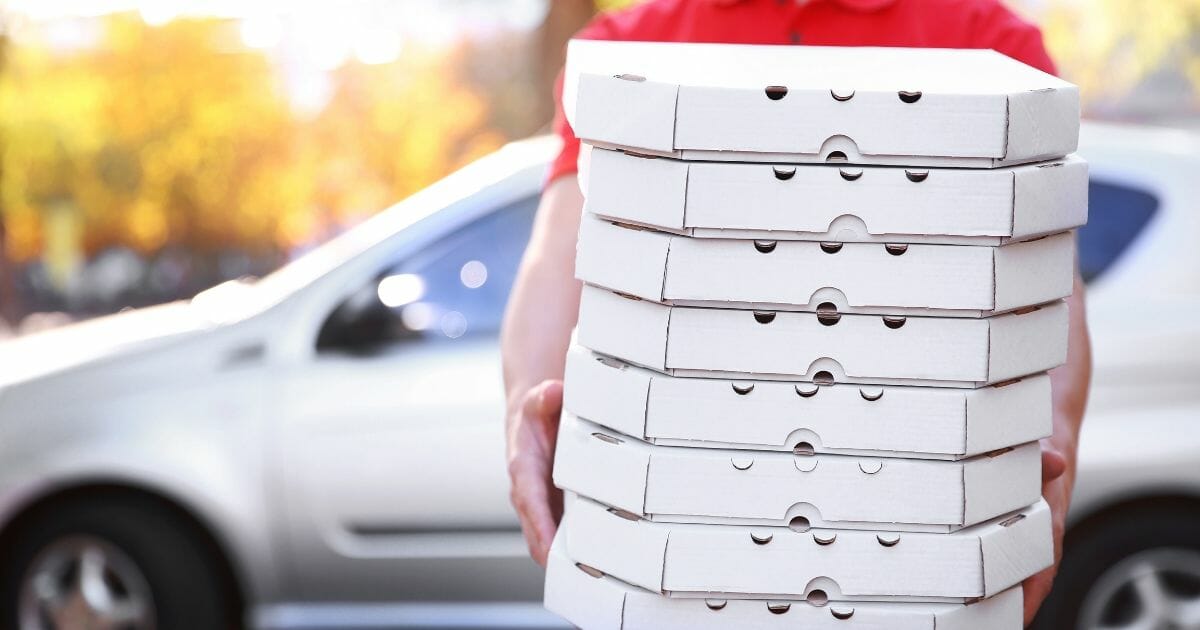 Pizza delivery boy holding boxes of pizza