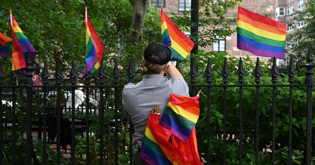 A National Park Service ranger places rainbow flags on the fence at the Stonewall National Monument in the West Village neighborhood of Greenwich Village in New York City on June 19, 2019.