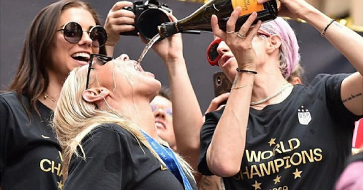 U.S. Women's National Soccer Team star Allie Long drinks chapagne poured by team co-captain Megan Rapinoe during the team's victory parade Wednesday in New York City.