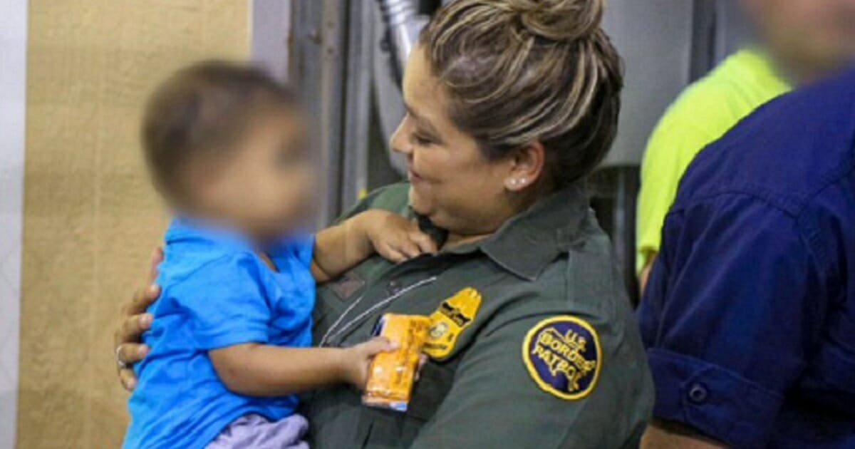Border Patrol agent holds a child.