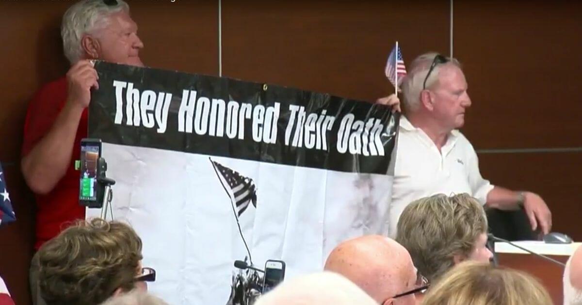 Attendees hold a banner during a city council meeting in St. Louis Park, Minn.