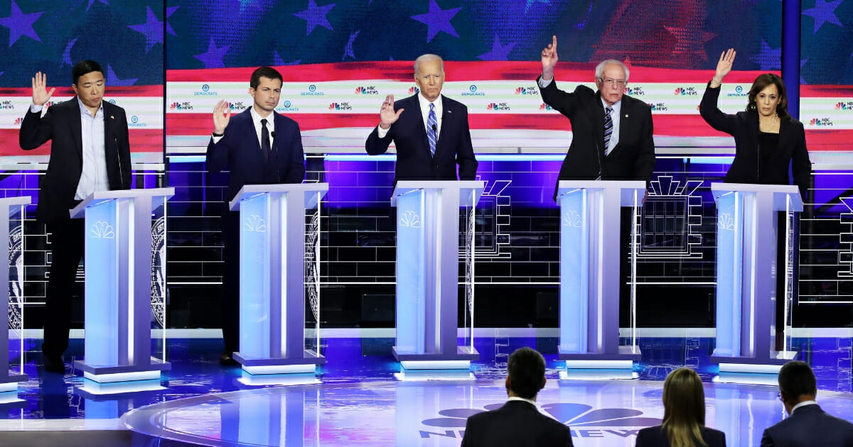 Democratic presidential candidates, from left, Andrew Yang, Pete Buttigieg, Joe Biden, Bernie Sanders and Kamala Harris raise their hands during a debate.