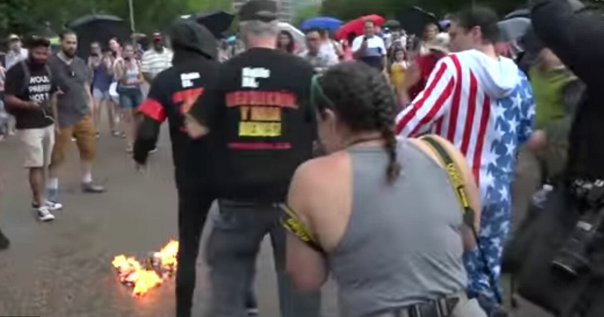 Protesters set an American flag on fire Thursday during the "Salute to America" July Fourth parade in Washington, D.C.