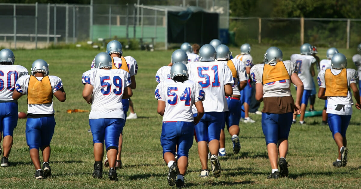 High school football players run during practice.