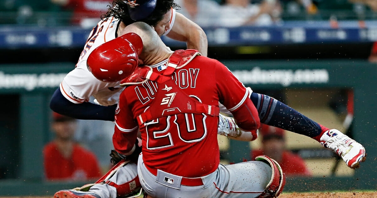 Jake Marisnick of the Houston Astros collides with catcher Jonathan Lucroy of the Los Angeles Angels as he attempts to score in the eighth inning at Minute Maid Park on July 7, 2019