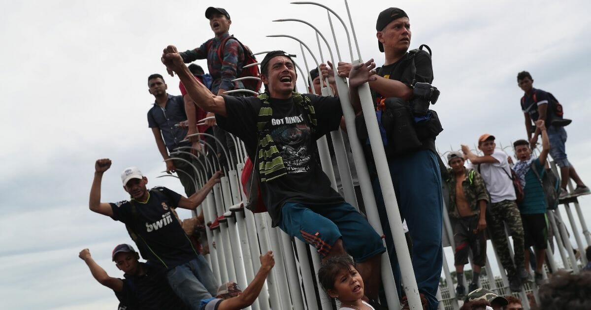 Members of a migrant caravan cheer during a clash with Mexican riot police at the border between Mexico and Guatemala on Oct. 19, 2018.