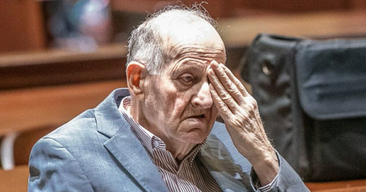 Albert Flick, 77, rubs his eye during his trial.