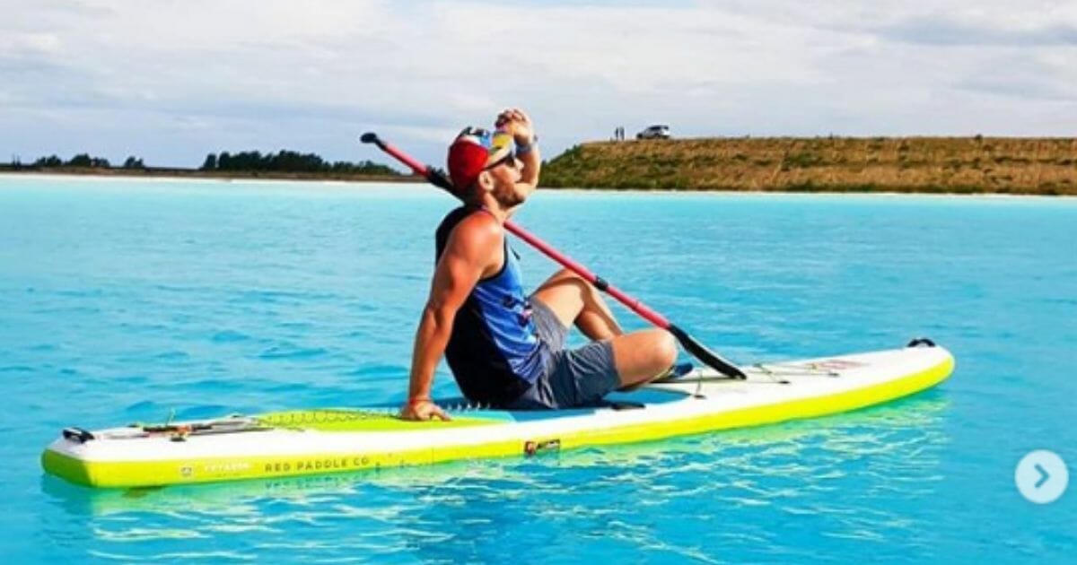 man on a paddleboard on a bright blue lake