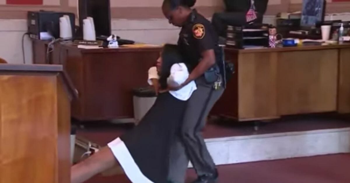Woman being dragged out of a court room