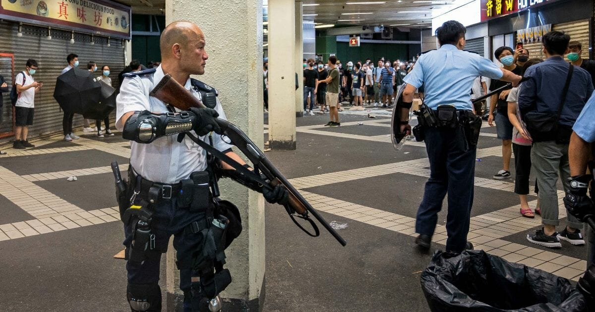 Armed riot cop squares off against Hong Kong protesters.