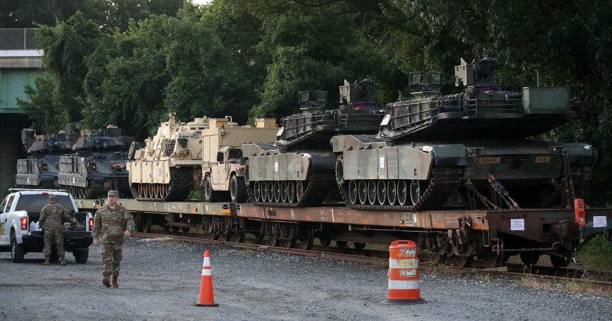 Two M1A1 Abrams tanks and other military vehicles sit on guarded rail cars Tuesday at a rail yard in Washington, D.C.