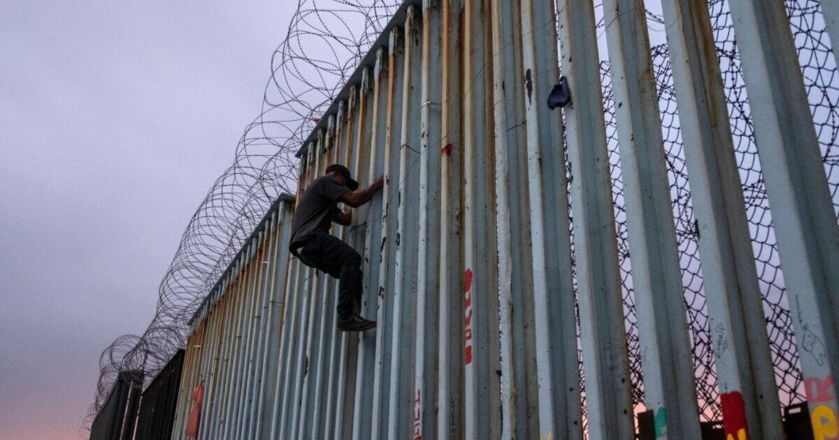 A man climbs a U.S.-Mexico border wall in Baja California