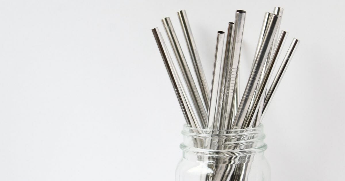 Stainless steel straws in glass jar with white copy space.
