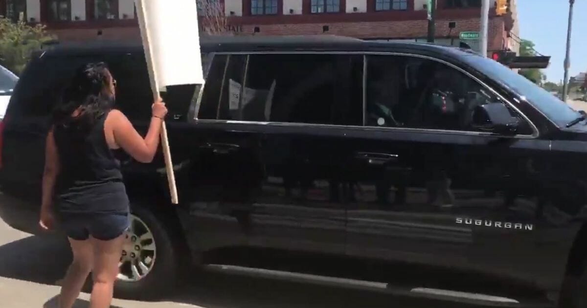 A protester yells at Joe Biden's vehicle at a traffic stop Thursday