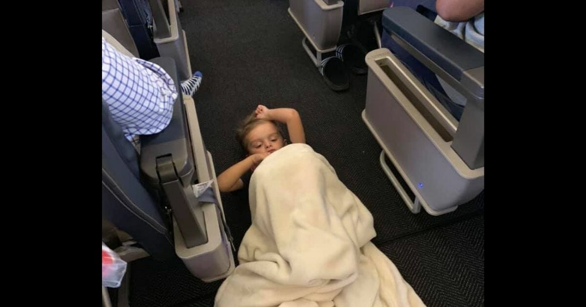 Brayson sleeps in the aisle of the plane.