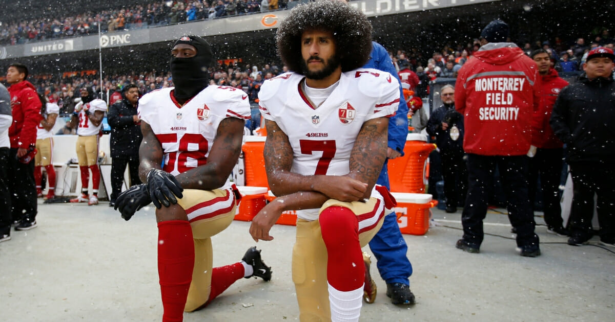 Eli Harold #58 and Colin Kaepernick #7 of the San Francisco 49ers kneel on the sideline, during the anthem, prior to the game against the Chicago Bears at Soldier Field on Dec. 4, 2016, in Chicago, Illinois.