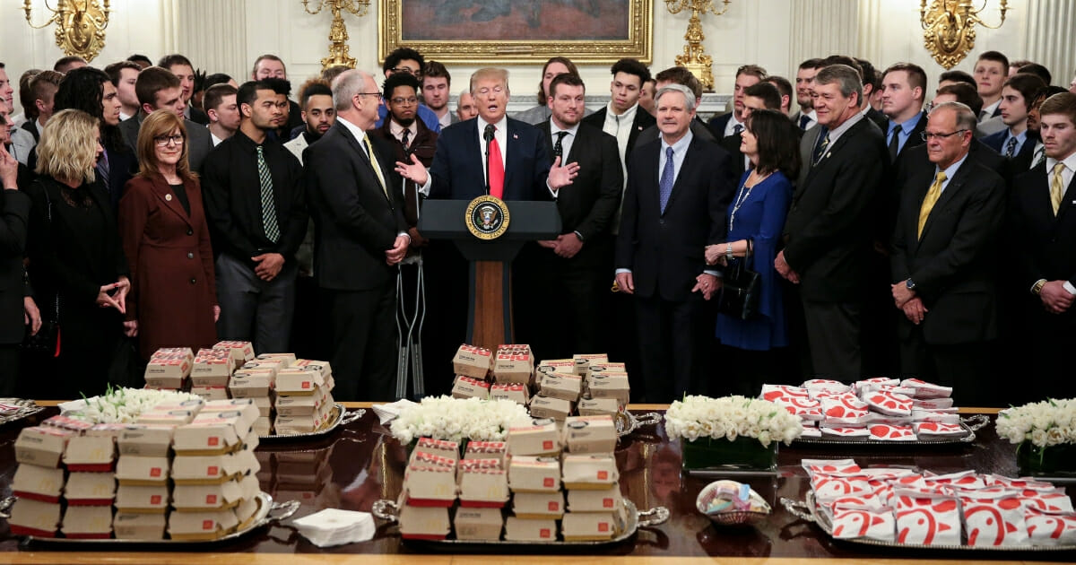 President Donald Trump speaks behind a table full of McDonald's hamburgers, Chick fil-A sandwiches and other fast food as he welcomes the 2018 Football Division I FCS champs North Dakota State Bison in the Diplomatic Room of the White House on March 4, 2019 in Washington, D.C.