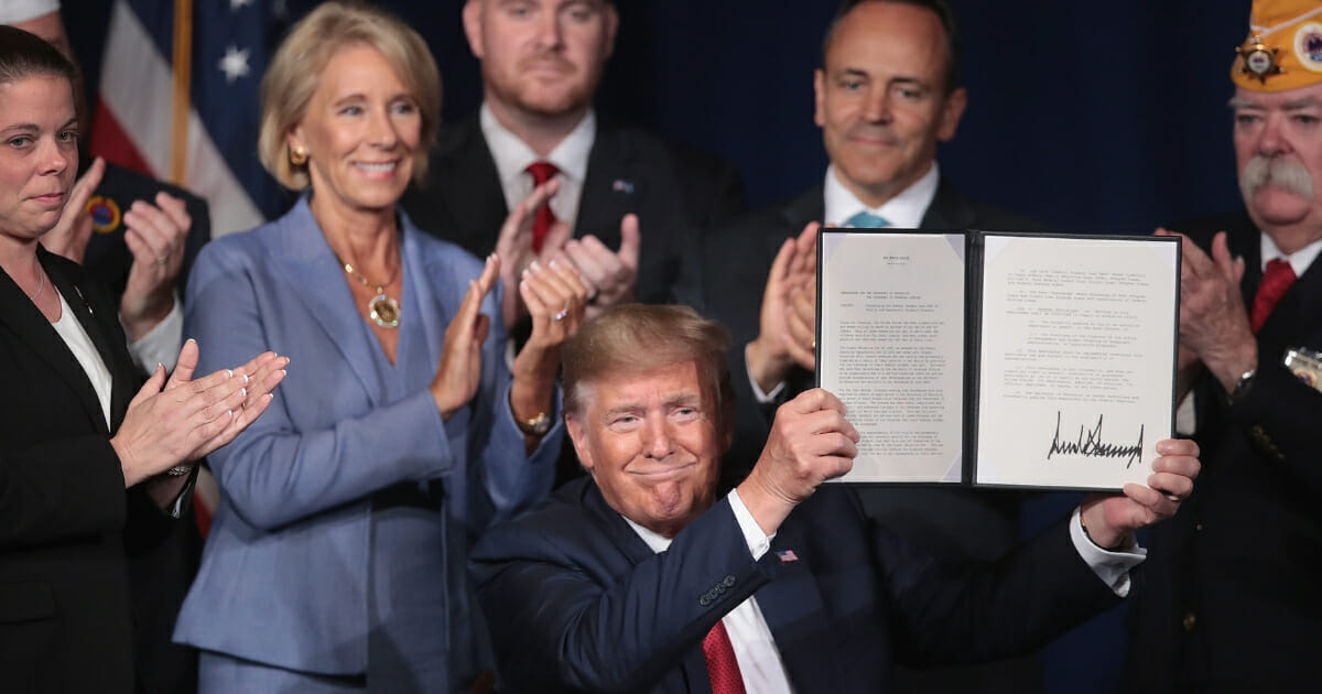 President Donald Trump signs a proclamation that will eliminate student loan debt for qualifying disabled veterans following a speech at the American Veterans' 75th National Convention at the Galt House on Aug. 21, 2019, in Louisville, Kentucky.