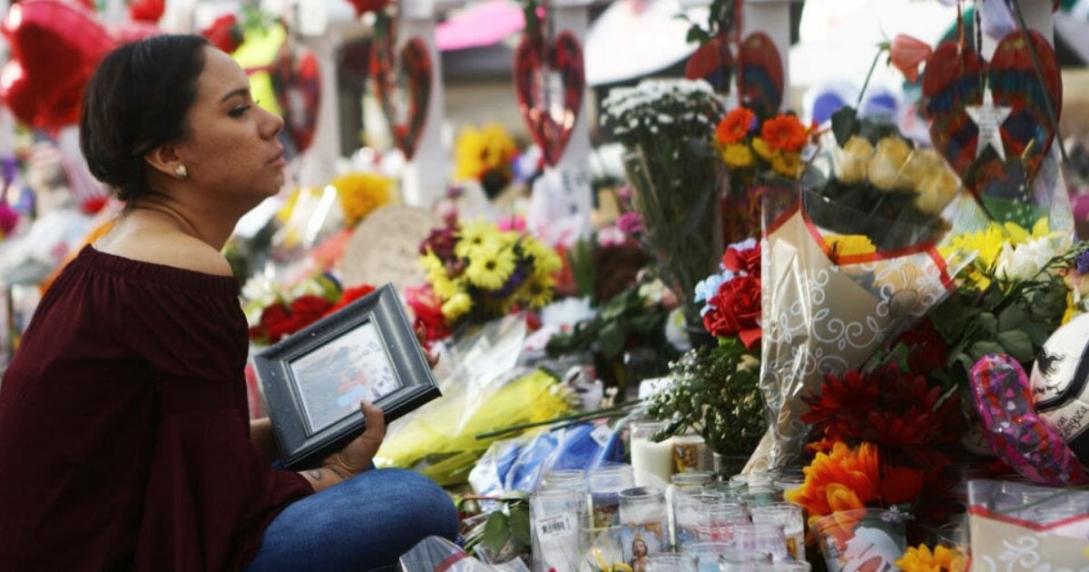 Yamileth Lopez holds a photo of her deceased friend Javier Amir Rodriguez at a makeshift memorial for shooting victims on Aug. 6, 2019, in El Paso, Texas.