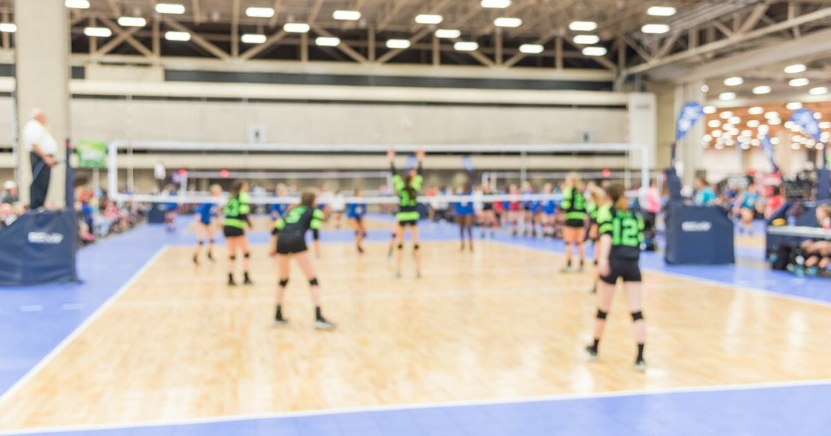 Blurred image group of teen girls playing indoor volleyball.