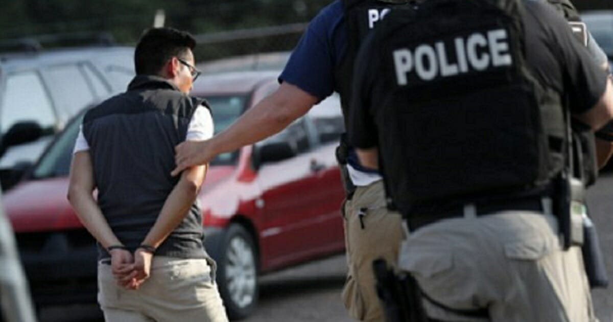 A man is led in handcuffs by police after an Immigration and Customs Enforcement raid in Mississippi on Wednesday.