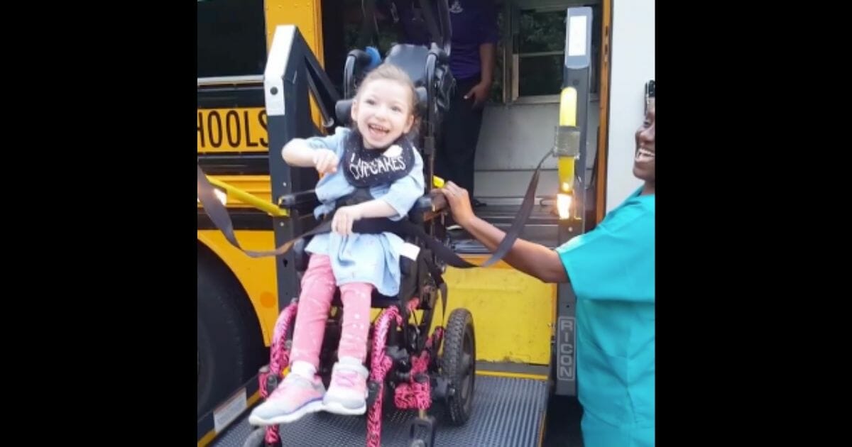 Little girl smiles and waves as she gets on bus