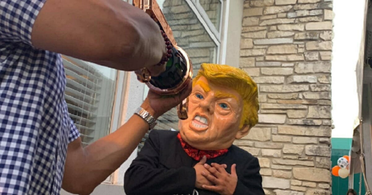 A man in a Donald Trump mask pretends to be shot.