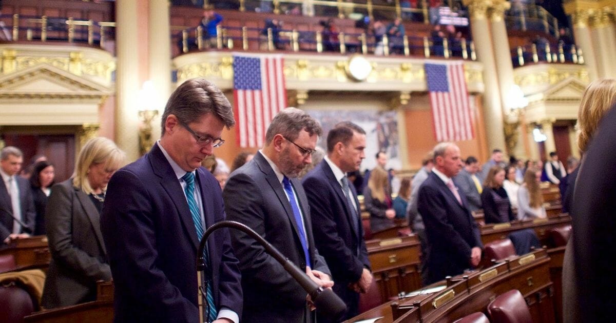Attendees pray before electors cast their votes in the House of Representatives chamber of the Pennsylvania Capitol Building on Dec. 19, 2016, in Harrisburg, Pennsylvania.