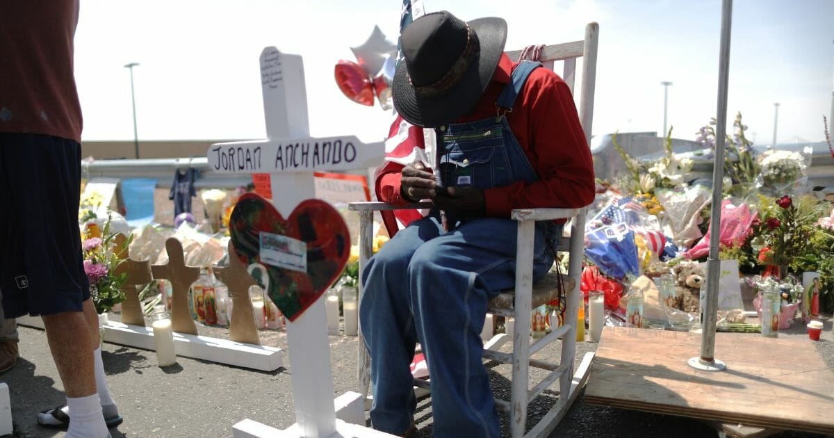 A man sits at a makeshift memorial near the scene of a mass shooting in El Paso, Texas.