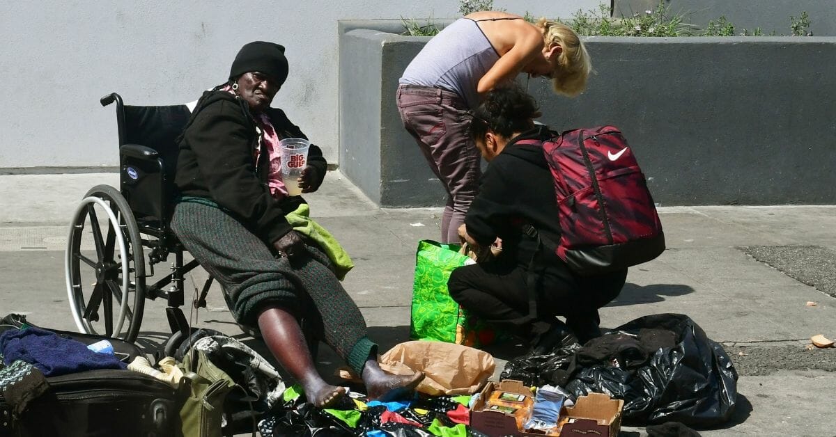 A homeless woman looks on from her wheelchair as others rummage through their belongings in Los Angeles, California on May 30, 2019.