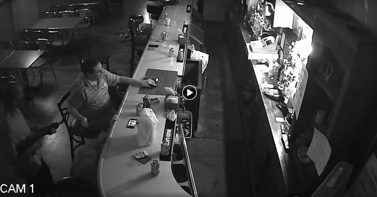 Man smokes while robber holds up bar.