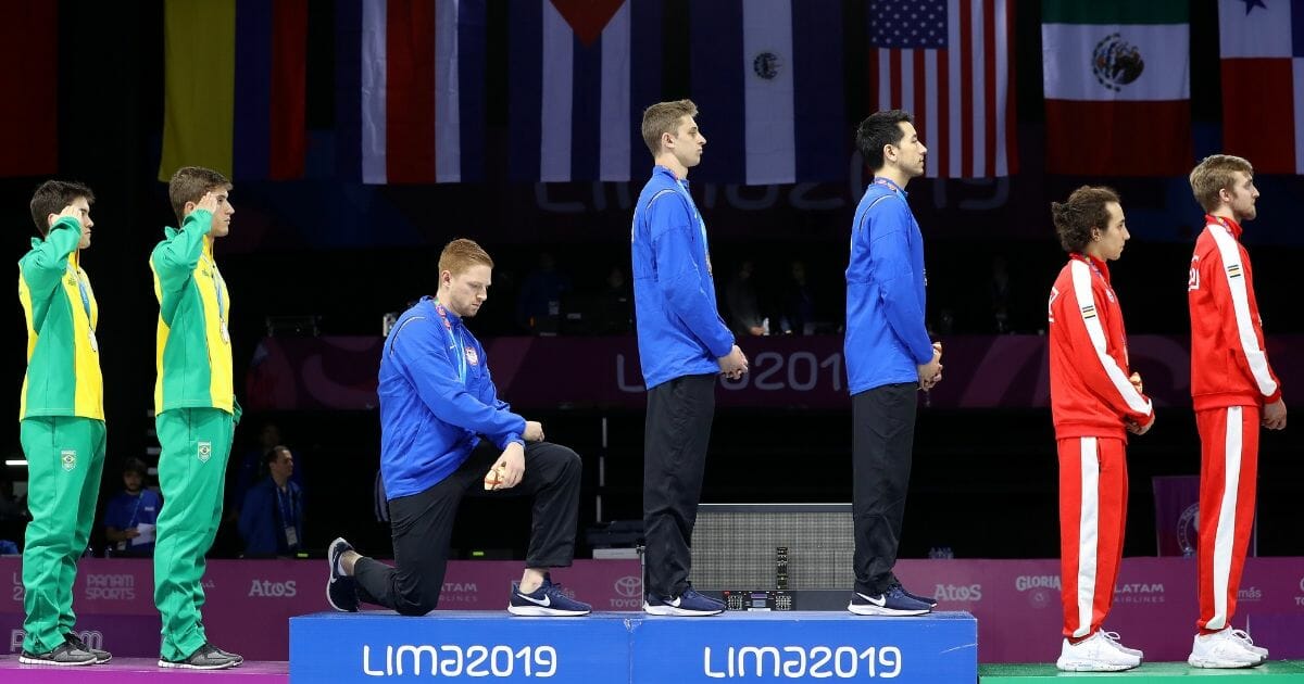 Gold medalist Race Imboden of United States takes a knee during the National Anthem Ceremony in the podium of Fencing Men's Foil Team Gold Medal Match Match on Day 14 of Lima 2019 Pan American Games at Fencing Pavilion of Lima Convention Center on August 09, 2019 in Lima, Peru.
