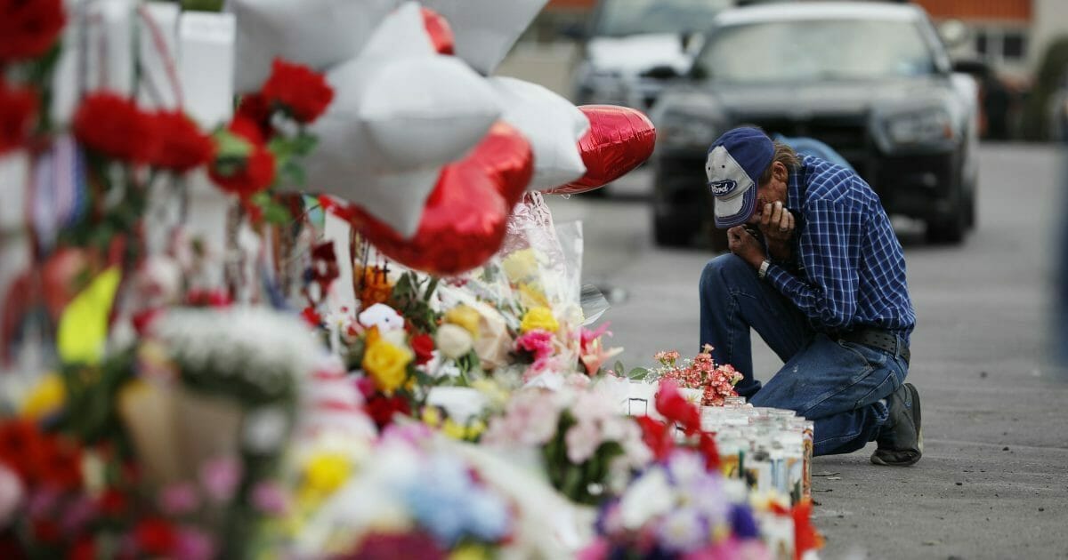A man cries beside a cross at a makeshift memorial near the scene of a mass shooting at a shopping complex Tuesday, Aug. 6, 2019, in El Paso, Texas.