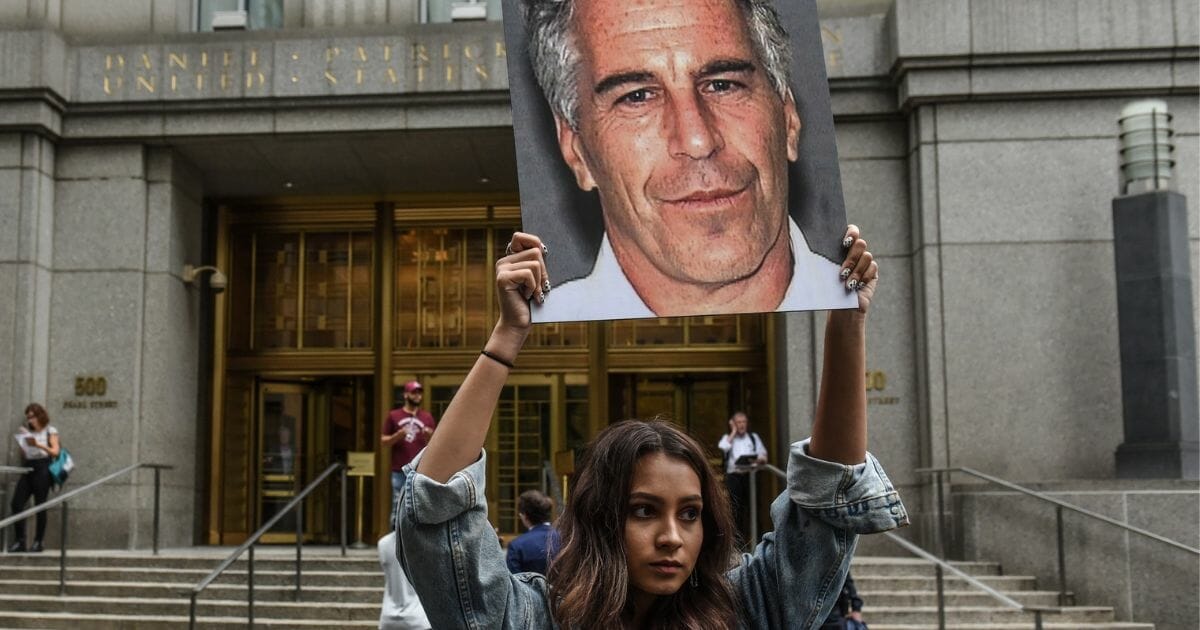 A protest group called "Hot Mess" hold up signs of Jeffrey Epstein in front of the federal courthouse on July 8, 2019 in New York City
