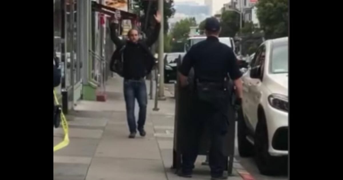 Man holds up hands in front of police