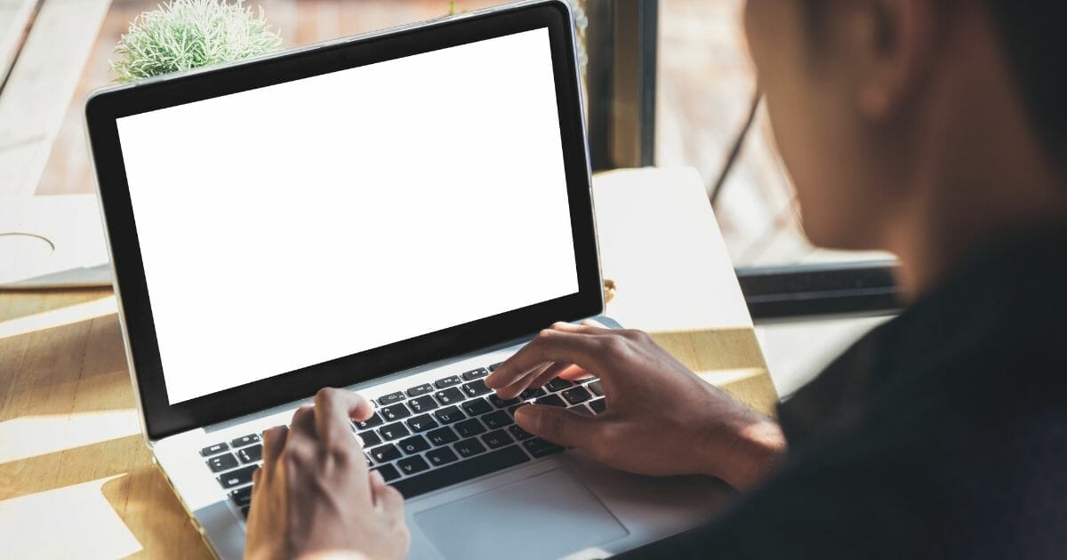 Young man working on his laptop with blank copy space screen