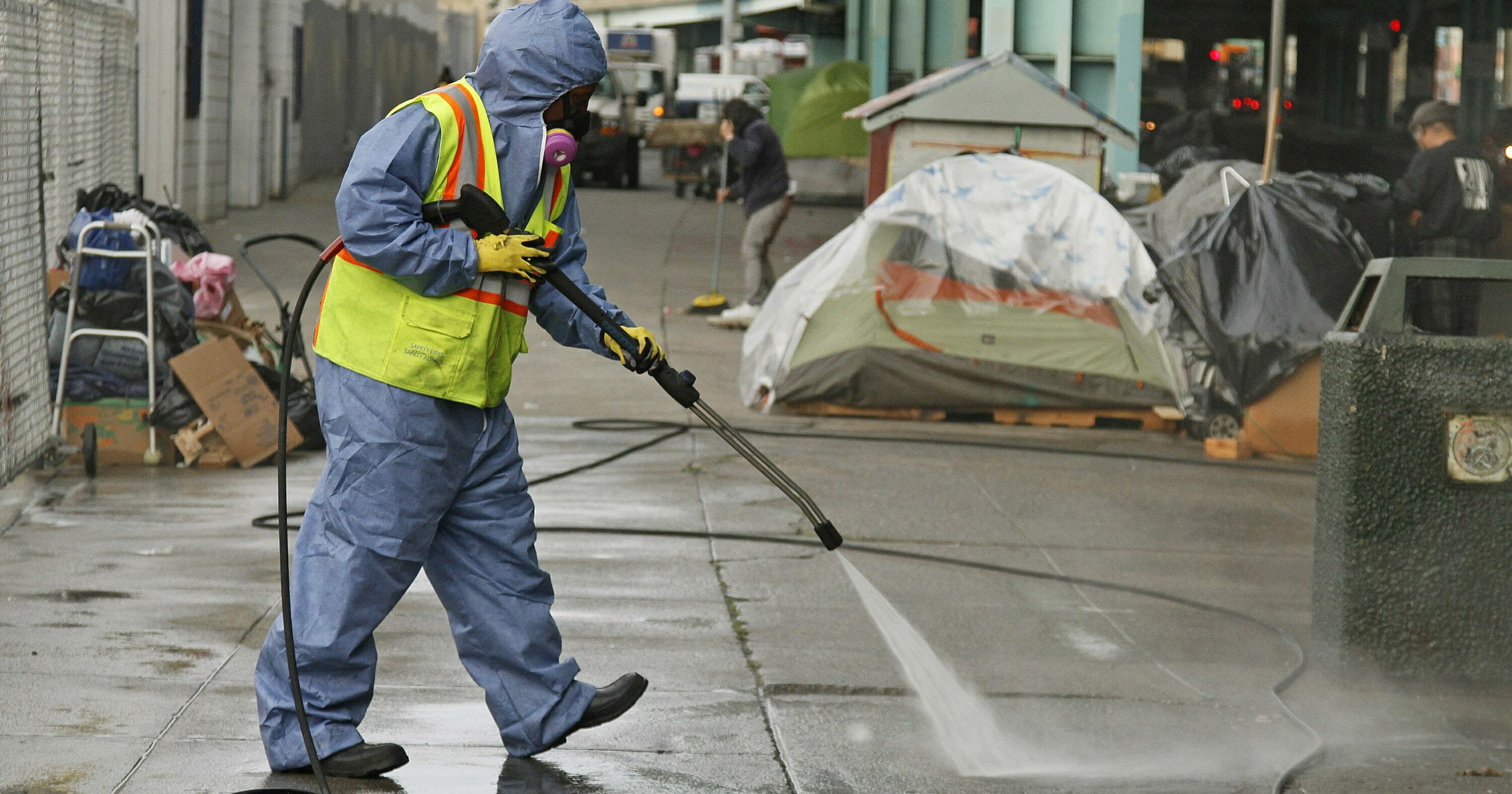 A city worker uses a power washer to clean the sidewalk by a tent city along Division Street in San Francisco on Feb. 26, 2016.