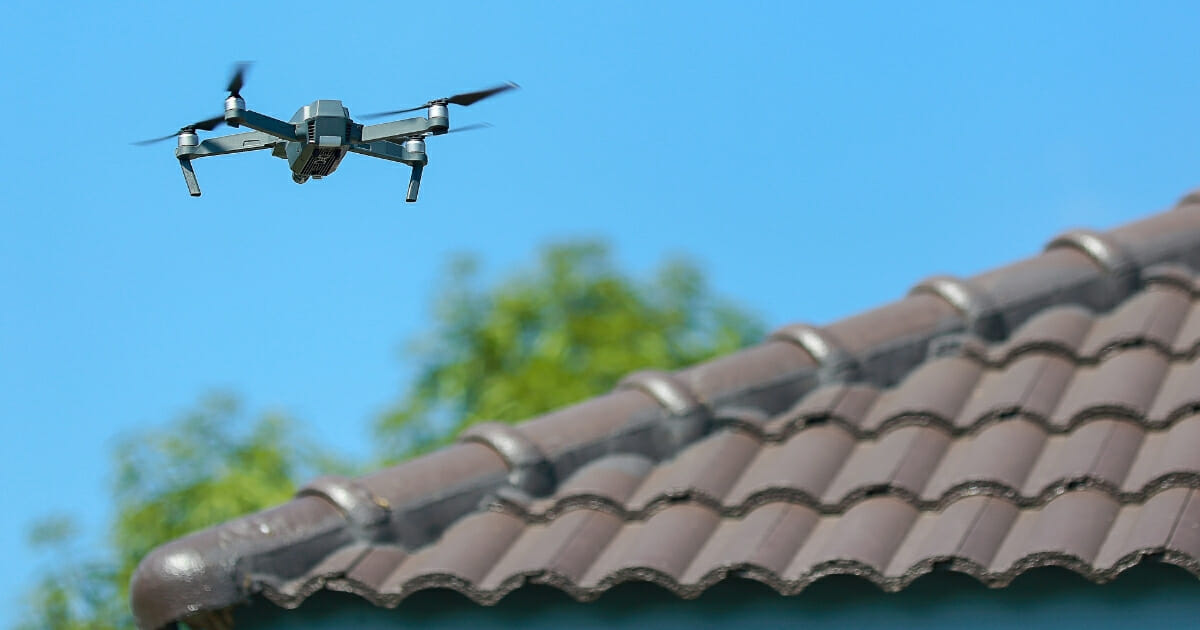A drone flies near the roof of a house.