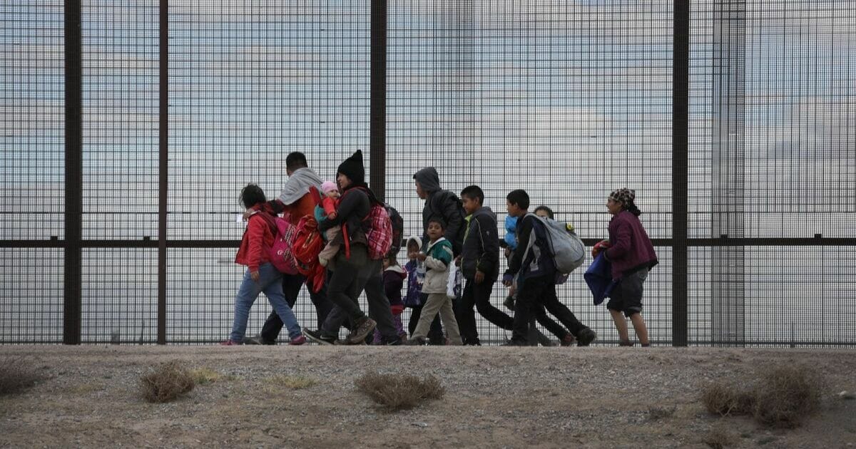 Central American immigrants walk along the border fence after crossing the Rio Grande from Mexico on Feb. 1, 2019, in El Paso, Texas.
