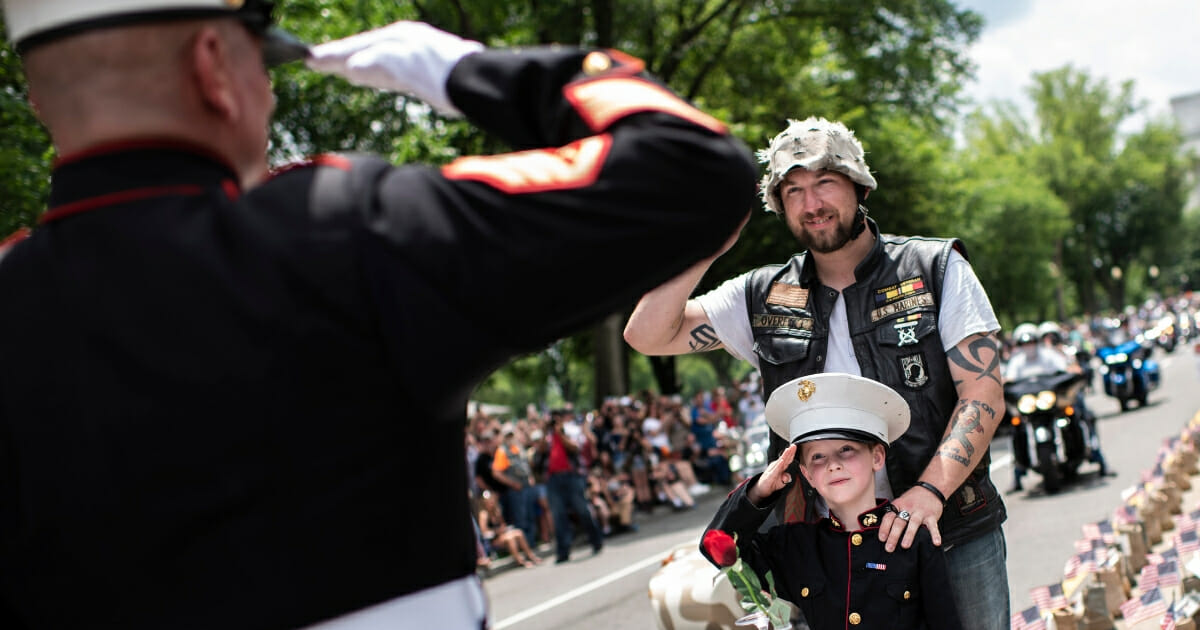 A father takes his son wearing a Marine uniform to salute Marine Staff Sgt. Tim Chambers, "the saluting Marine," as they take part in the "Rolling Thunder" parade, part of the Memorial weekend honoring war veterans in Washington, D.C., on May 26 2019.