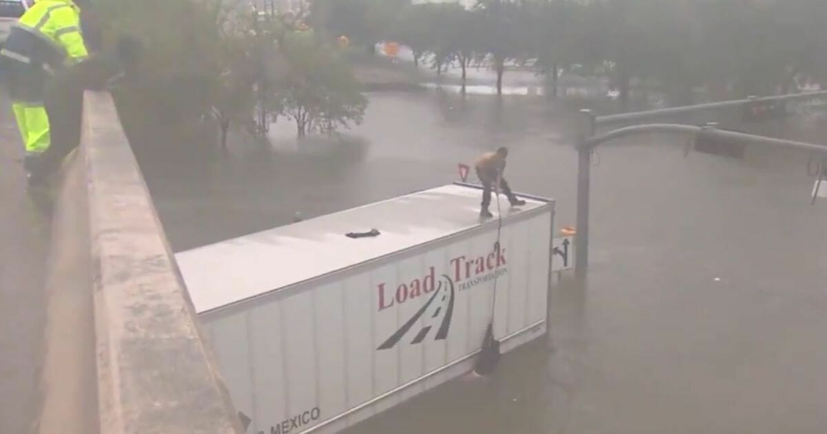 A good Samaritan rescues a man trapped inside his truck in rising floodwaters.