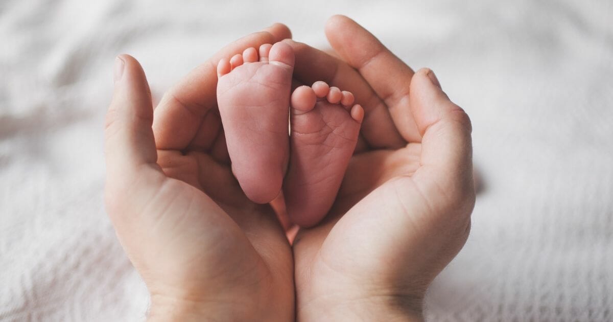 Parent holding feet of newborn baby.