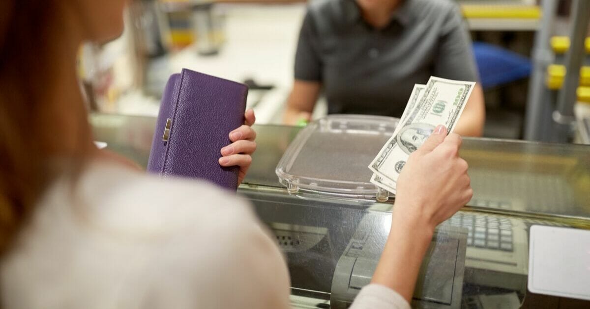 Woman pays cashier with cash.