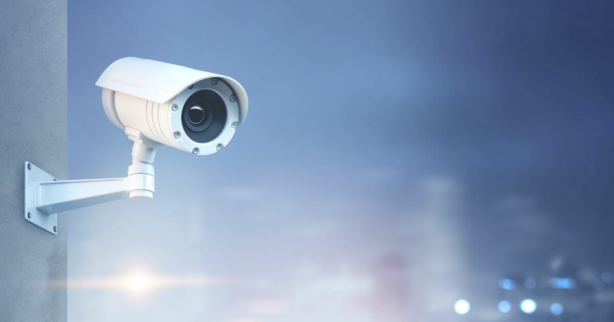 Stock image of a surveillance camera on a wall.