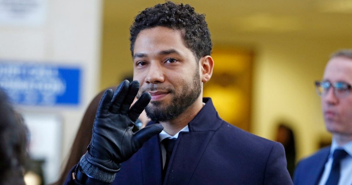 A smug-looking Jussie Smollett waves to the camera as he leaves a Chicago courthouse in March after the state's attorney's office dropped charges against the actor of filing a false report.