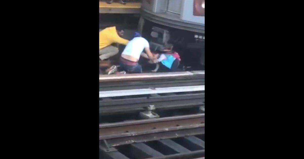 Rescuers come to the aid of a young girl after her father pulled her with him in front of an oncoming train.