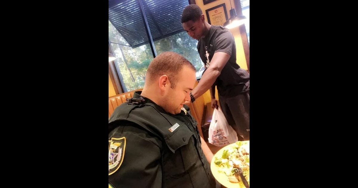 A young man named Juan O'Neal stops to pray for Officer Cameron Tucker of the Volusia County Sheriff's Office in DeLand, Florida.