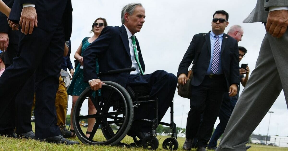 Texas Gov. Greg Abbott is pictured in a file photo from 2018 using a wheel chair to cross the grounds of a high school in Santa Few that was the scene of a shooting.