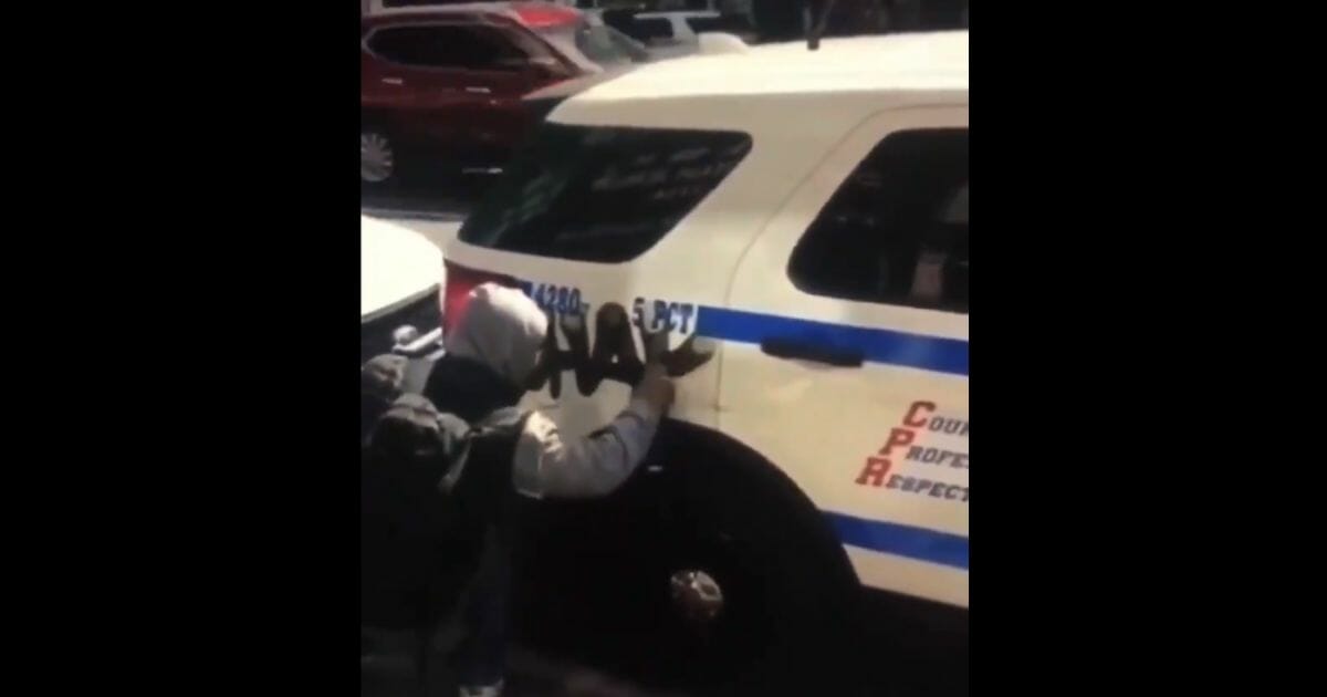 Vandal painting an NYPD car.