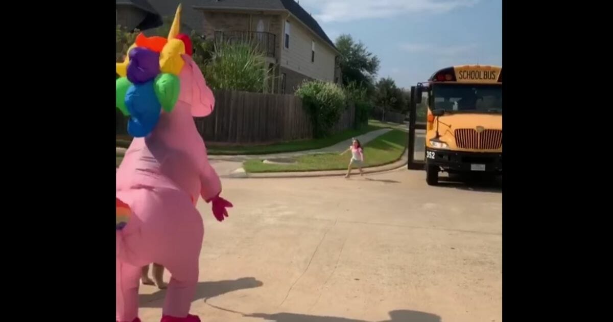 Mom surprises daughter at bus stop dressed in unicorn costume.